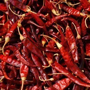 Pile of dried de arbol chiles on a white background