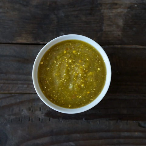 White bowl of Green Mexican Salsa on a dark wooden surface
