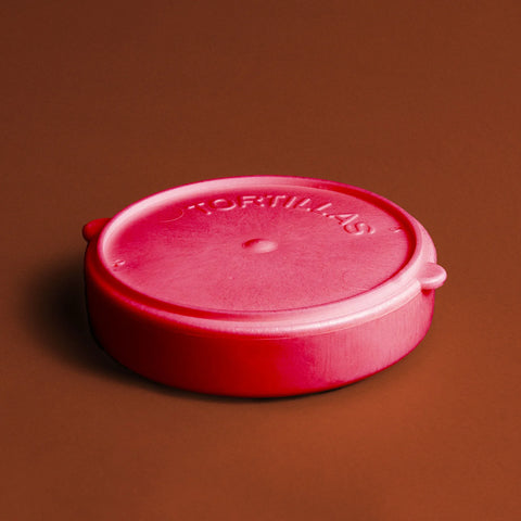 Red plastic tortilla warmer on burnt orange background.