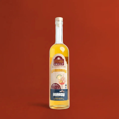 A tall, thin glass bottle of Agave syrup on a red background