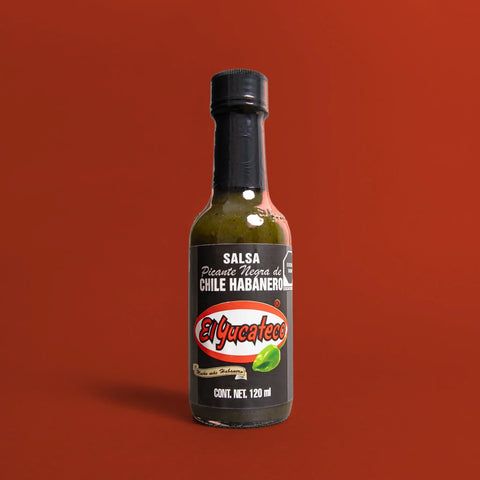 Bottle of El Yucateco hot sauce on a red background