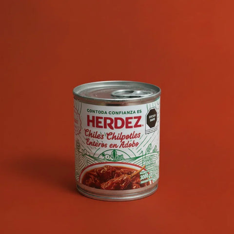 A can of Herdez Chipotle peppers on a red background