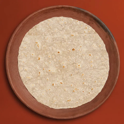 Round tortilla on a wooden plate against a red background