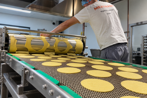 Machine with 'Mextrade Mercado Mexicano' branding on a production line with tortilla.
