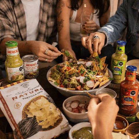 People enjoying a meal with nachos, salsa, and other ingredients on a table.