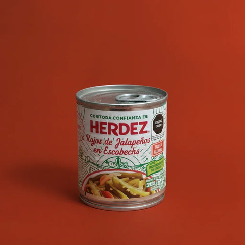 A white can of Herdez sliced jalapeno peppers on a red background