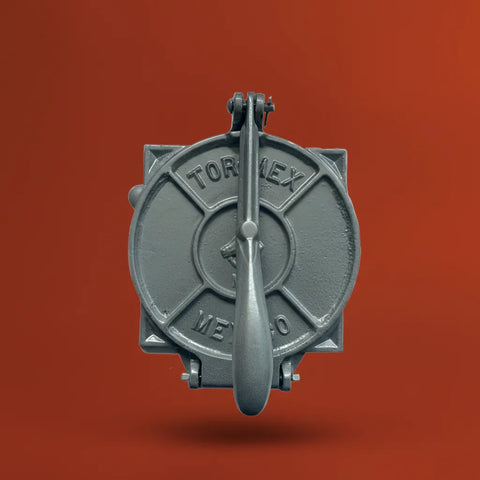 Metallic tortilla press with 'Tormex' branding on a red background
