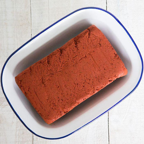 Rectangular block of achiote paste on a white plate with blue rim