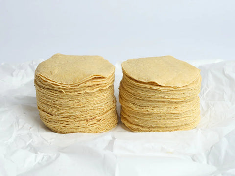 Two stacks of yellow corn tortillas on a white background