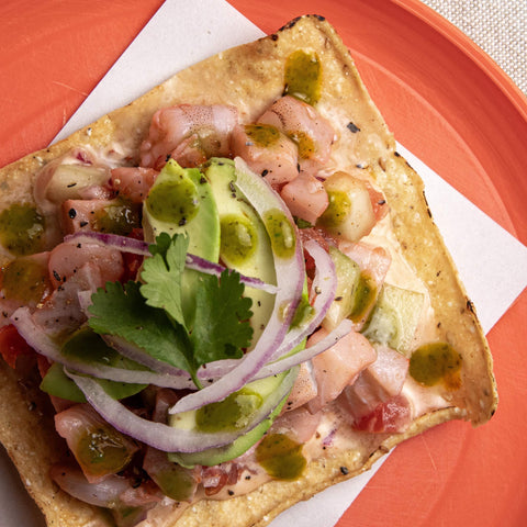 Tortilla with seafood and avocado on a red plate