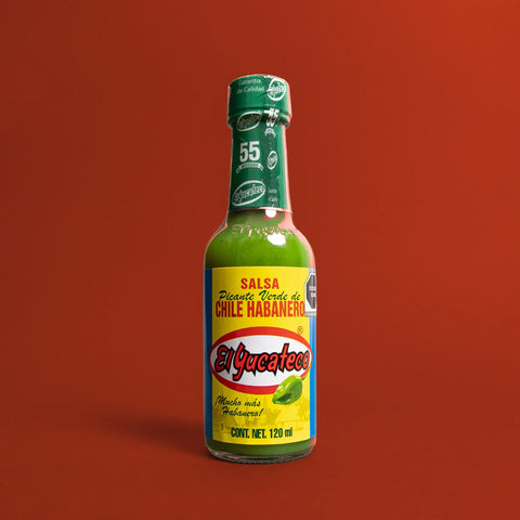 El Yucateco green hot sauce bottle on a red background