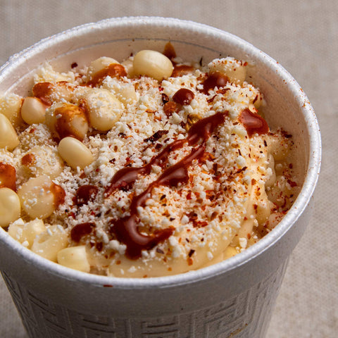 Macaroni and cheese and hot sauce drizzle in a white bowl.