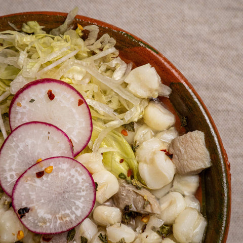 Plated dish with shredded cabbage, radish slices, and other ingredients on a textured surface.