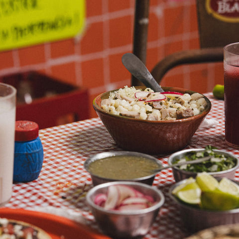 Bowl of food on a table with condiments and drinks in a casual setting