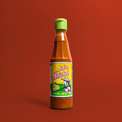 Bottle of Limon Hot sauce by Huichol on a red background