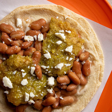 Tortilla with beans and green sauce on a orange plate